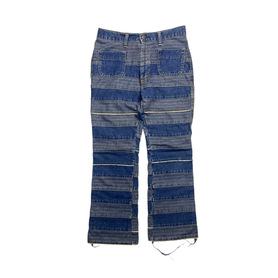 Pair of blue denim pants with a patchwork design on a white background